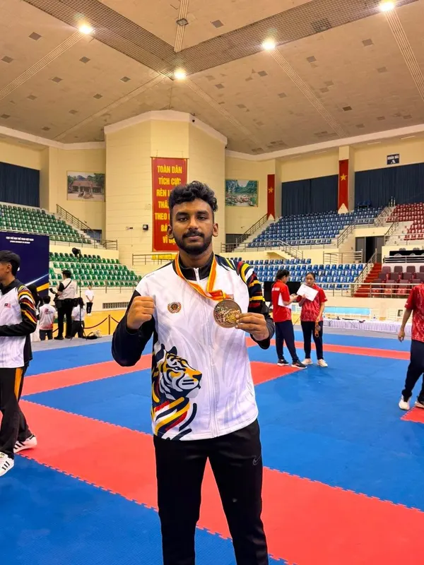 Master Navinessan Vickneswaran holding his Southeast Asia bronze medal in the competition arena